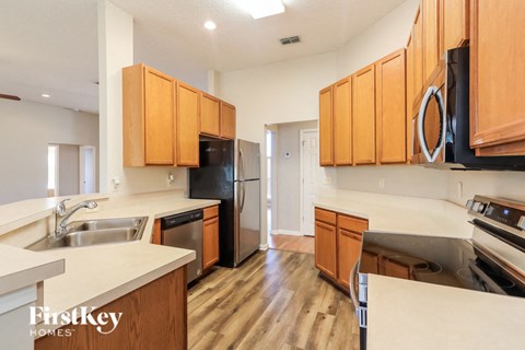 A kitchen with wooden cabinets and a black fridge.