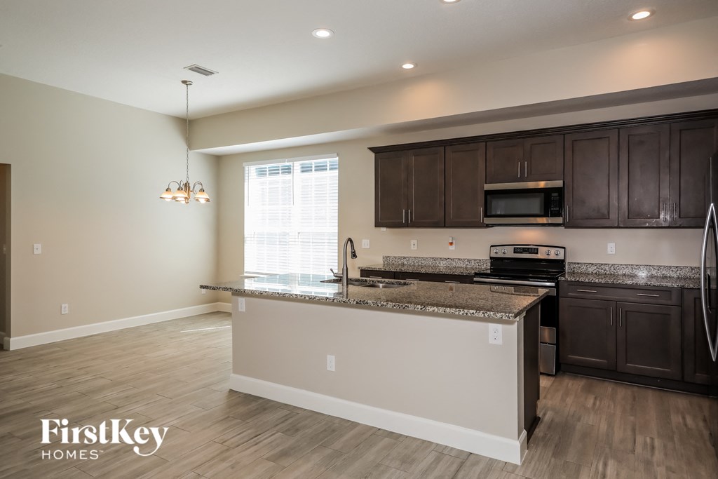 a kitchen with a granite counter top and dark wood cabinets