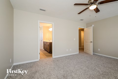 a spacious living room with carpet and a ceiling fan