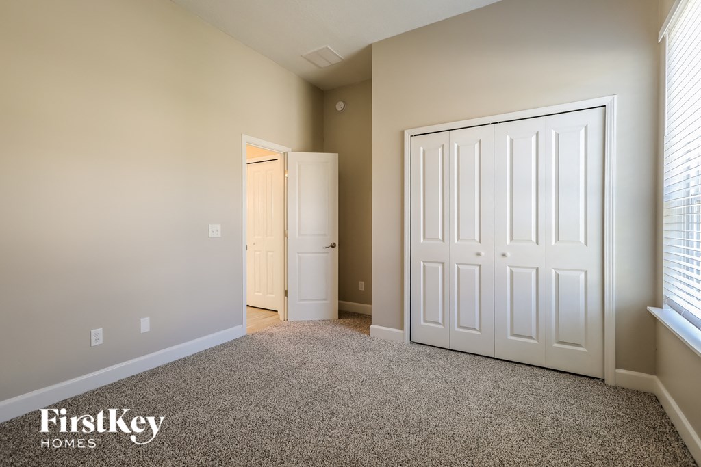 a bedroom with two closets and a door and a carpeted floor