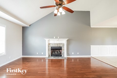 A spacious living room with a fireplace and a ceiling fan.