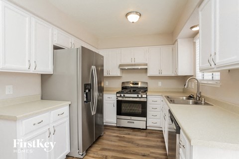 A kitchen with white cabinets and a stainless steel refrigerator.