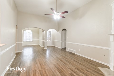 an empty living room with hardwood floors and a ceiling fan