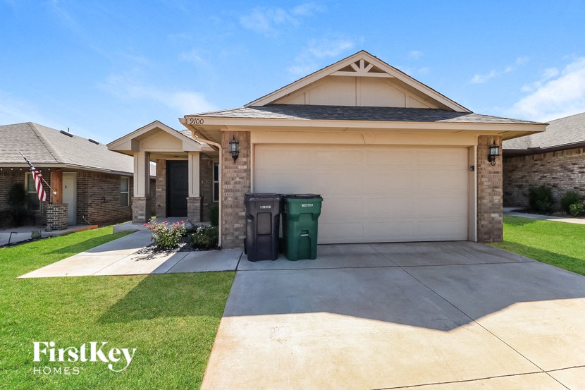 a house with a driveway and trash cans in front of it