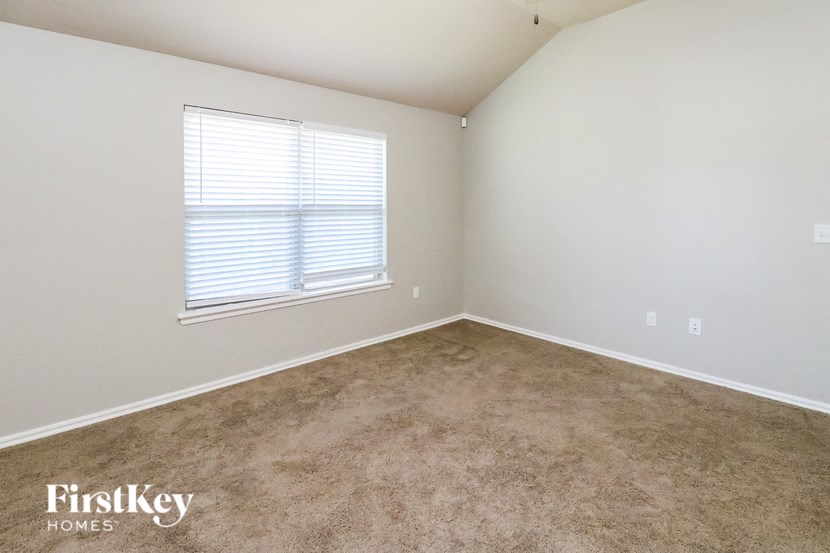 a carpeted room with a window and white walls