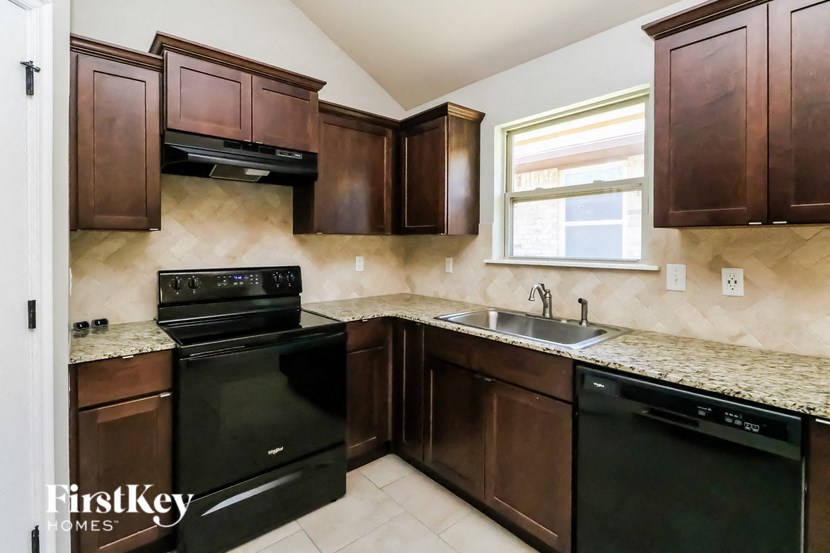 full view of the kitchen with black appliances and granite counter tops