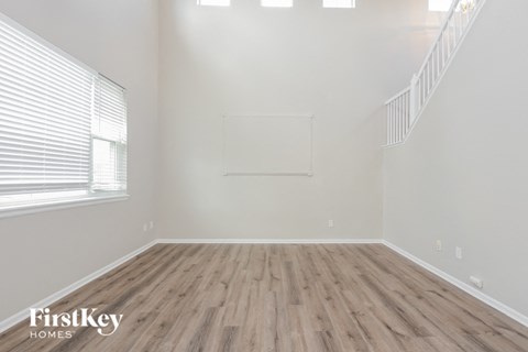 the living room of an empty house with wood flooring and a window
