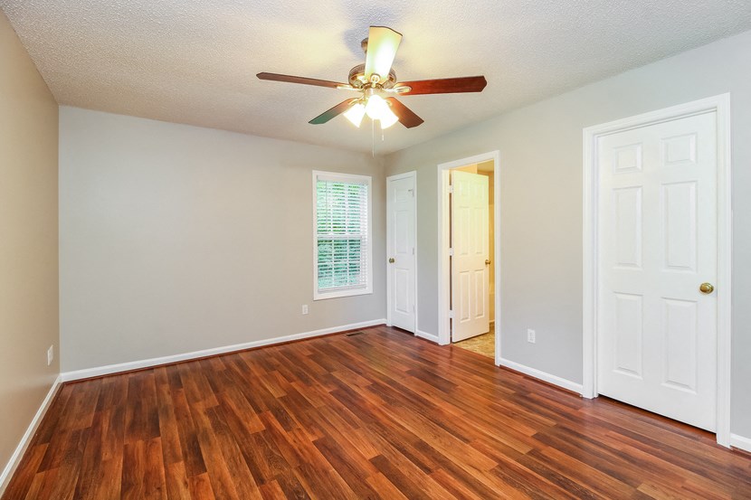 an empty living room with wood floors and a ceiling fan
