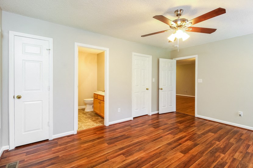 an empty living room with wood floors and a ceiling fan
