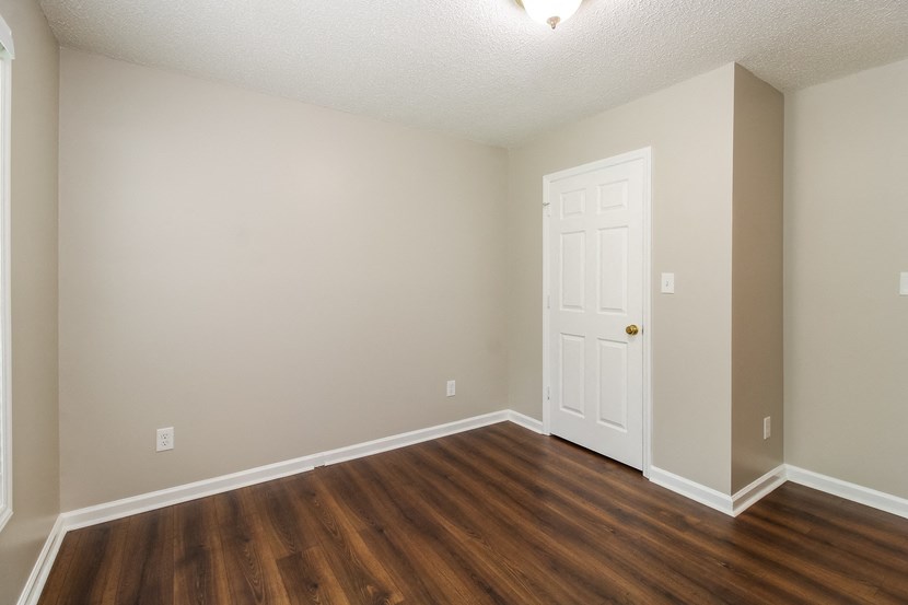 an empty living room with wooden floors and a white door