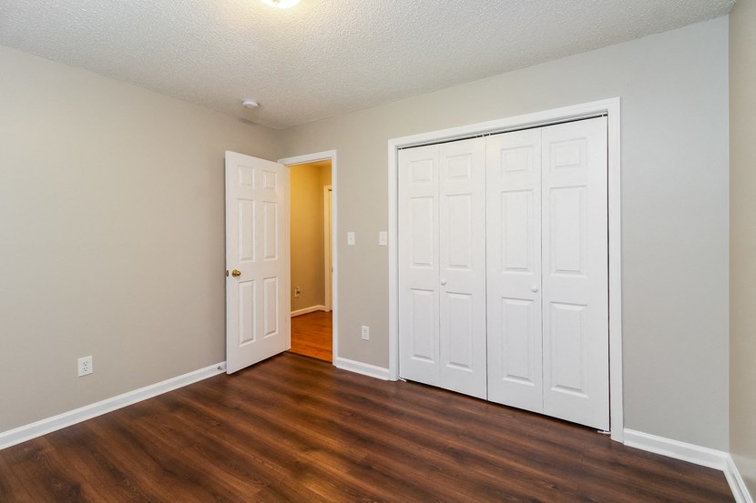 an empty living room with white doors and wood flooring