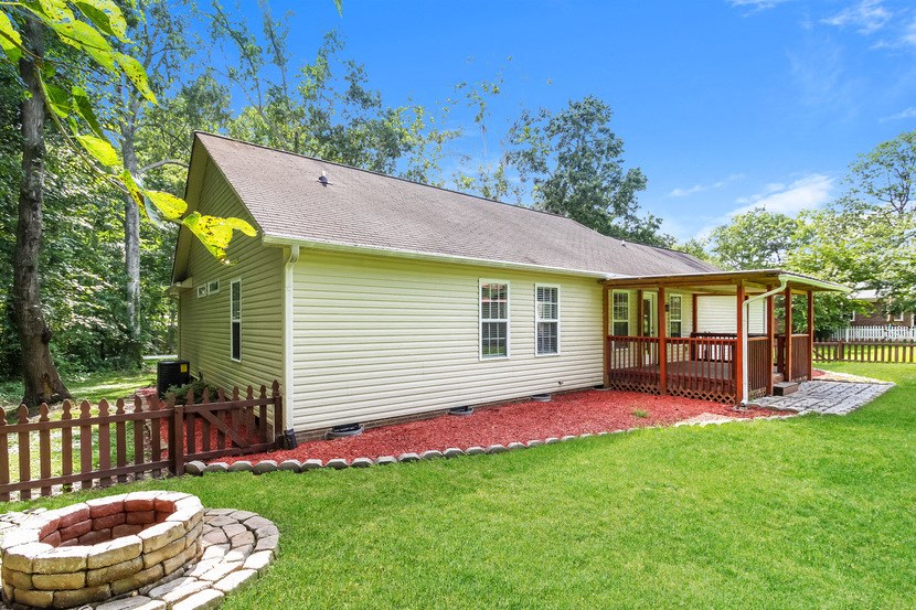 a small yellow house with a backyard with a patio and a fire pit