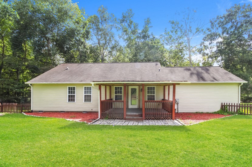 the front of a white house with a porch and a grassy yard