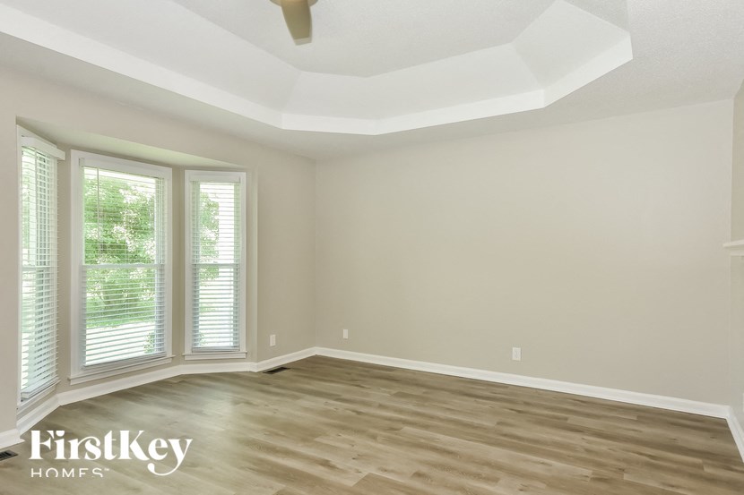 the living room of a home with wood flooring and large windows