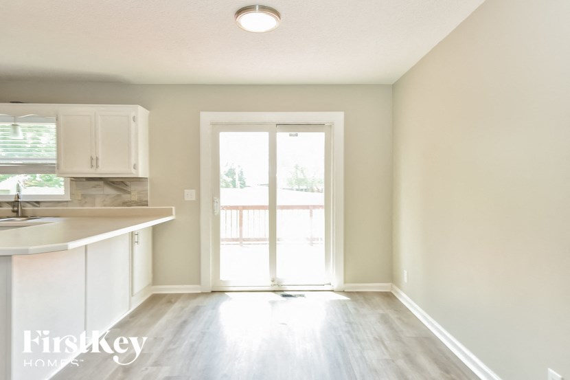 an empty kitchen with white cabinets and a door to a patio