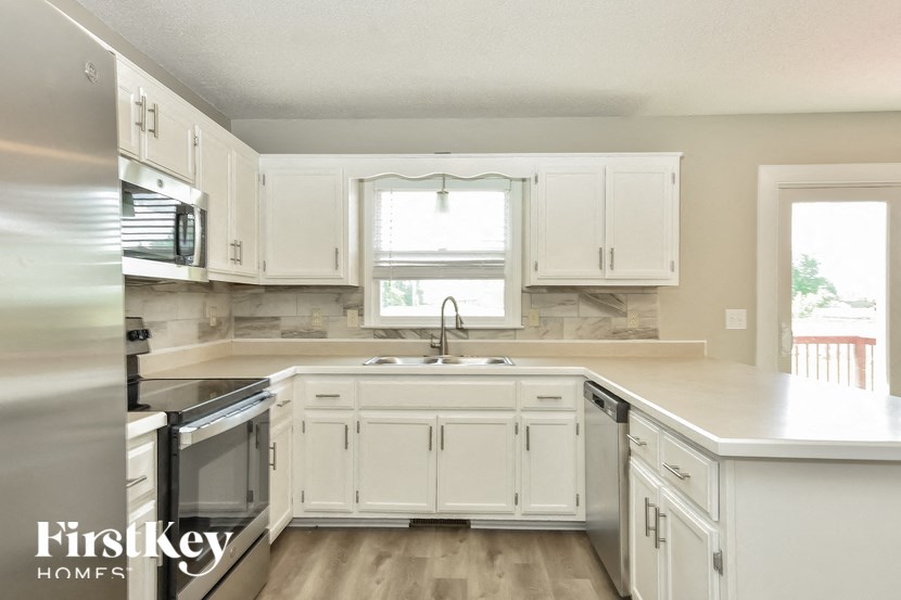 a kitchen with white cabinets and a sink and a window