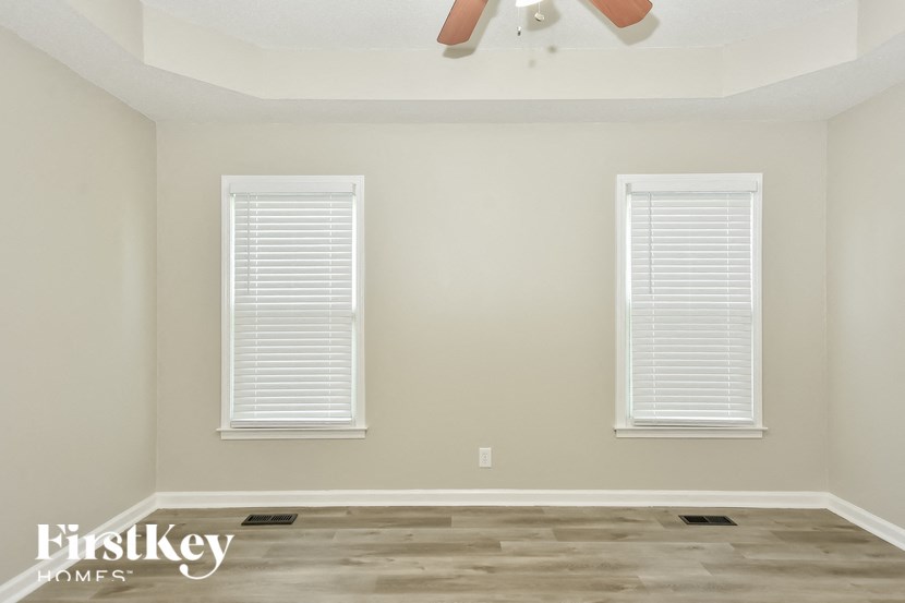 a empty room with two windows and a ceiling fan