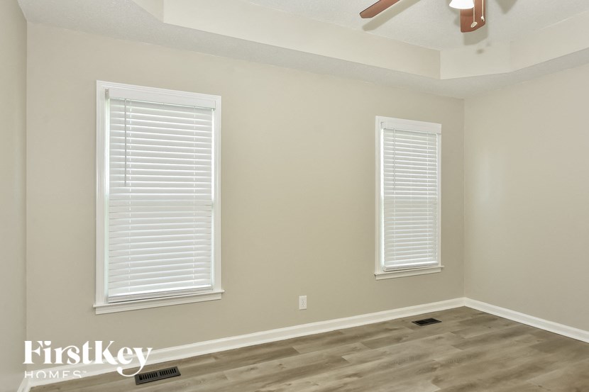 a empty room with two windows and a ceiling fan