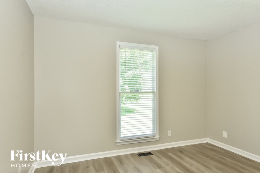 a window in an empty room with wooden floors and a window blinds