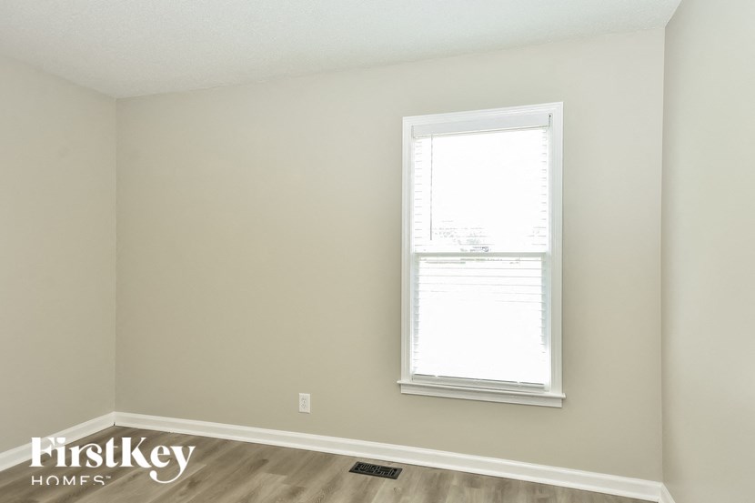 a bedroom with a window and a wood floor