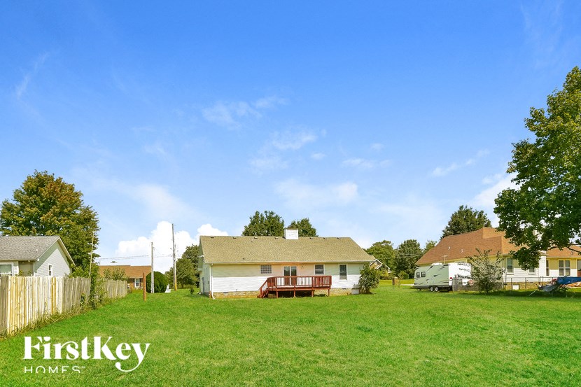 a backyard with a house and a green field