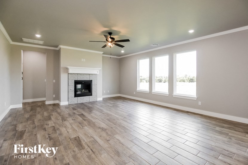an empty living room with a fireplace and a ceiling fan