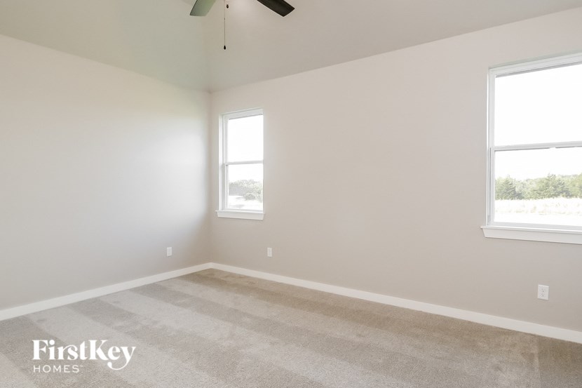 a bedroom with two windows and a carpeted floor