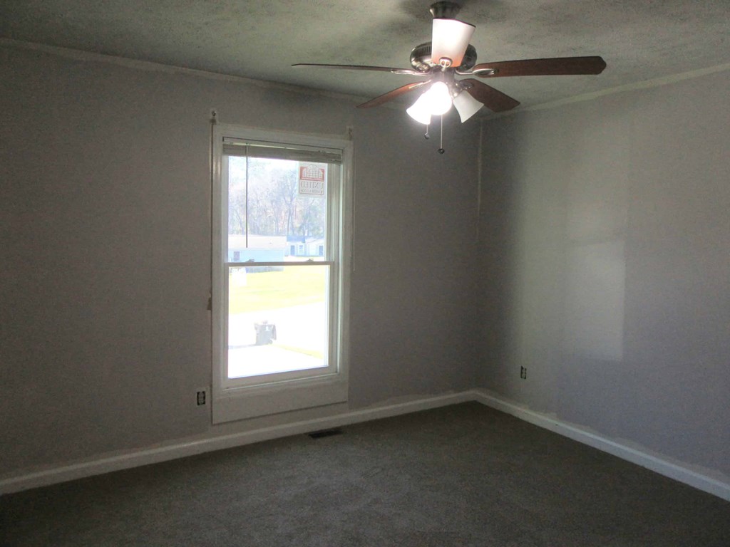 an empty room with a window and a ceiling fan