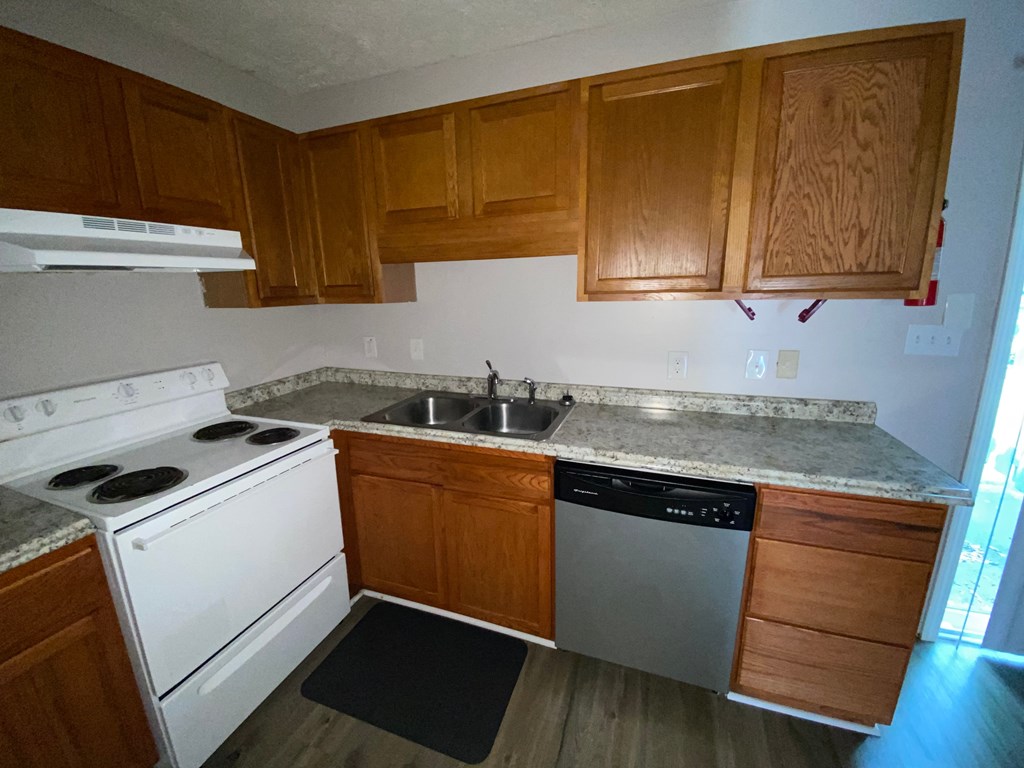 an empty kitchen with wooden cabinets and white appliances