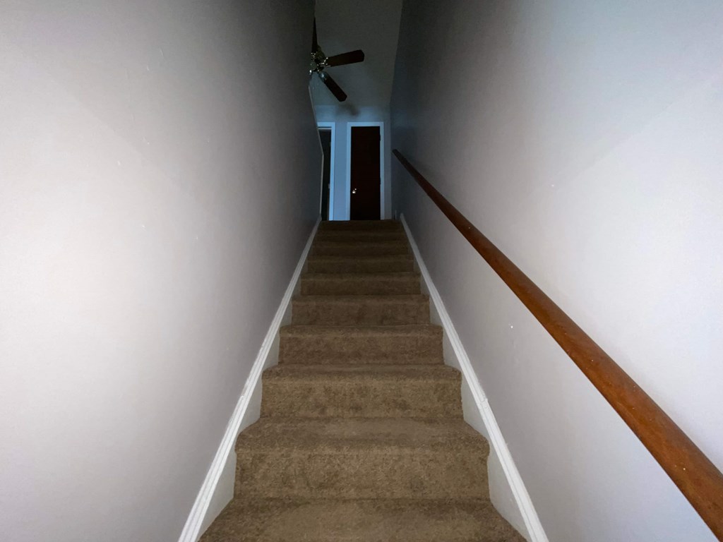 stairs leading up to a hallway with a ceiling fan