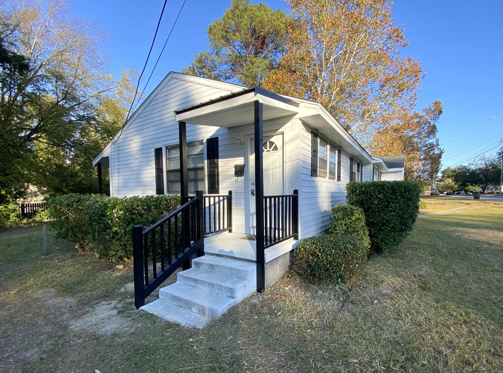 the front of a white house with a porch and stairs
