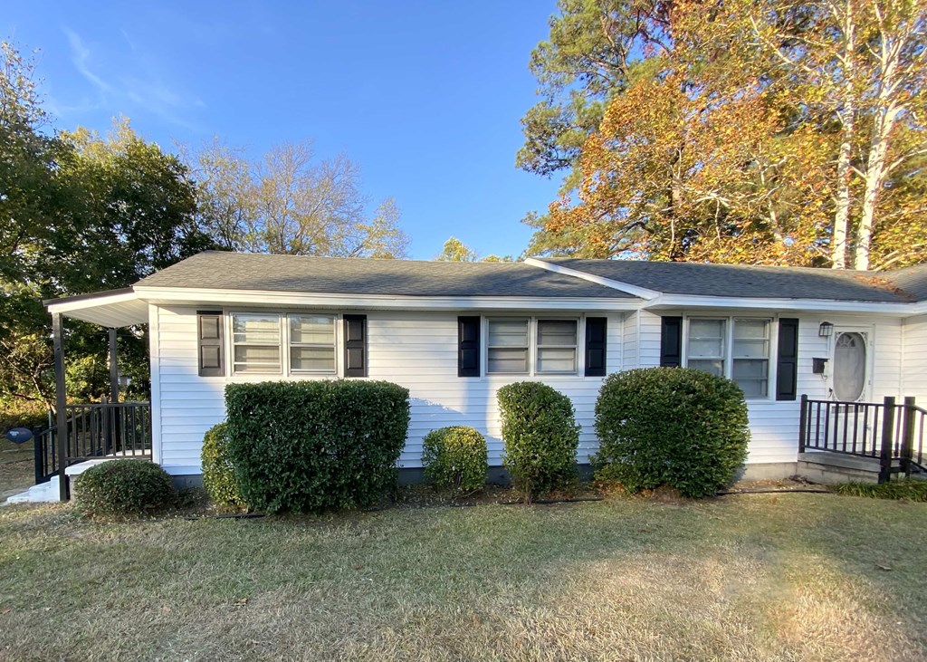 a small white house with a yard and bushes