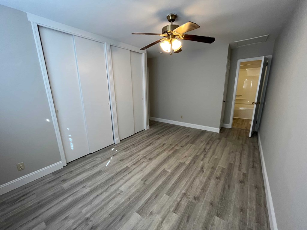 a bedroom with wood flooring and a ceiling fan