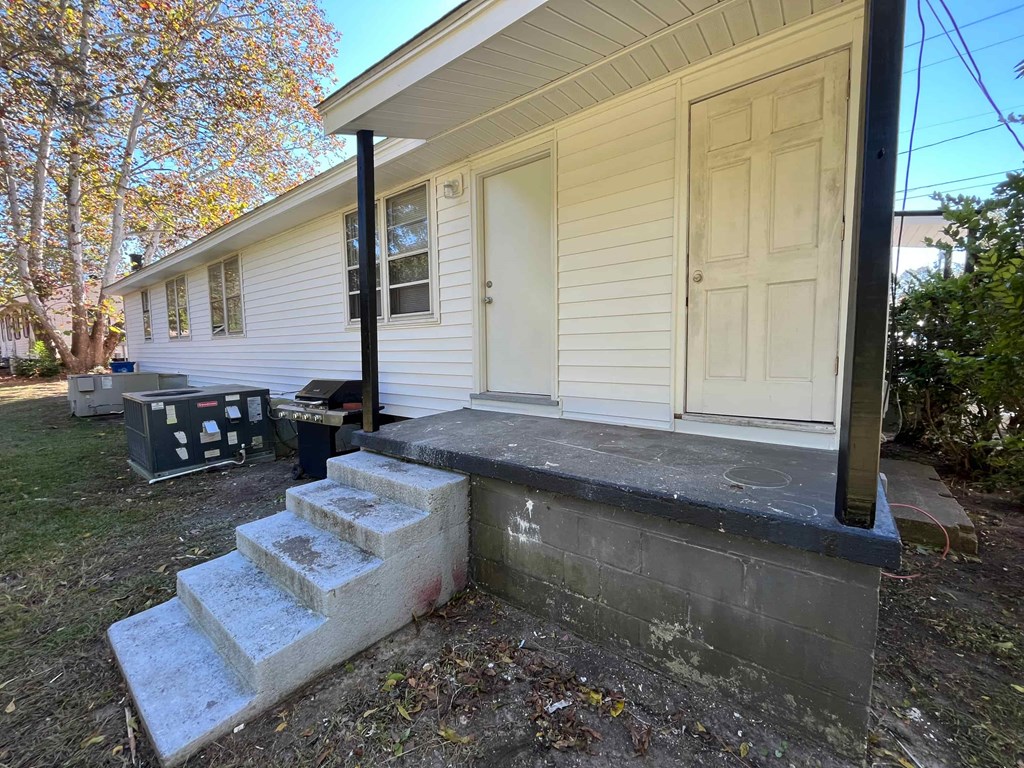 the front door of a white house with steps and a porch