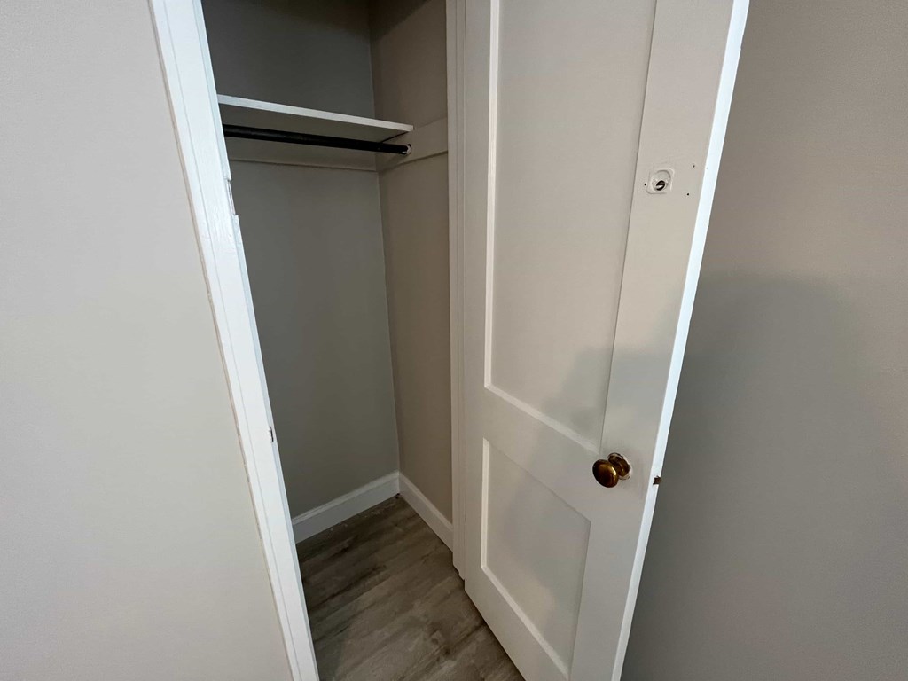 a walk in closet with a white door and a closet shelf