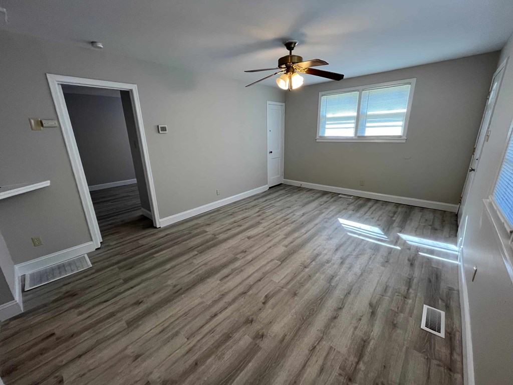 a empty living room with wooden floors and a ceiling fan