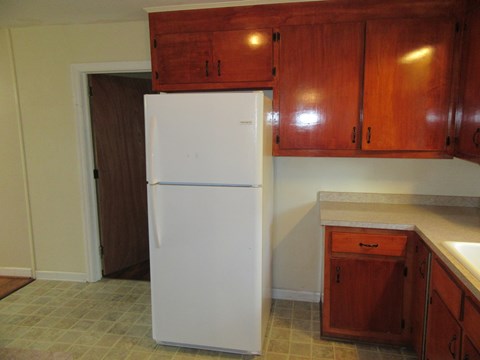 A white refrigerator in a kitchen with brown cabinets.