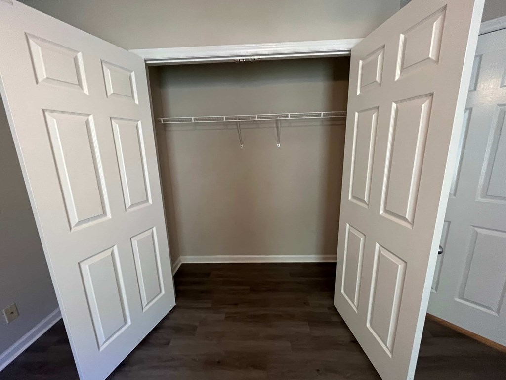 a empty closet with white doors and a wood floor