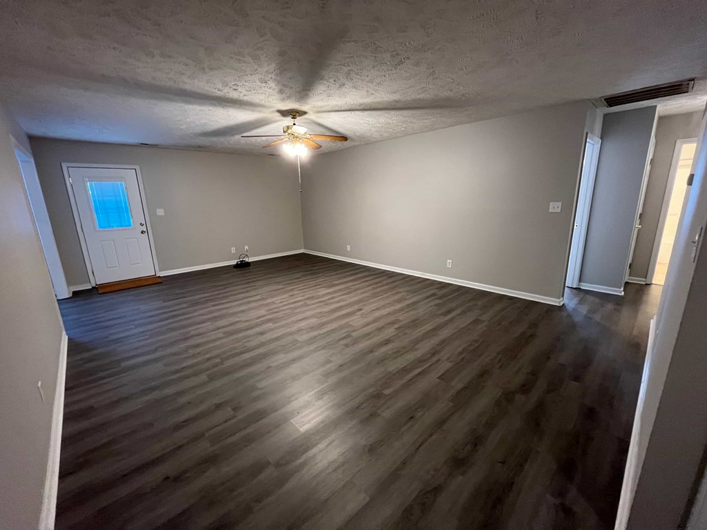 a empty living room with wood floors and a ceiling fan