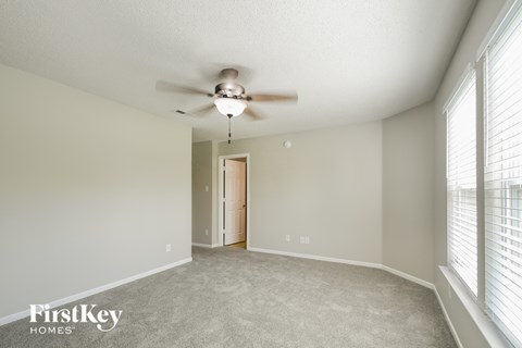 the spacious living room with ceiling fan and large windows