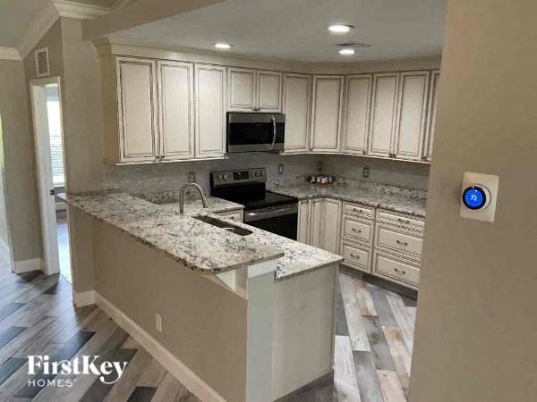 a kitchen with white cabinets and a marble counter top