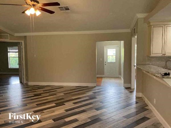 an empty living room and kitchen with a ceiling fan