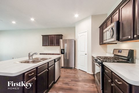 A kitchen with dark brown cabinets and a stainless steel refrigerator.