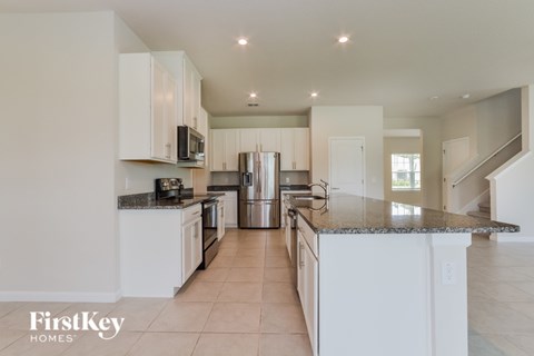 A kitchen with white cabinets and a granite countertop.