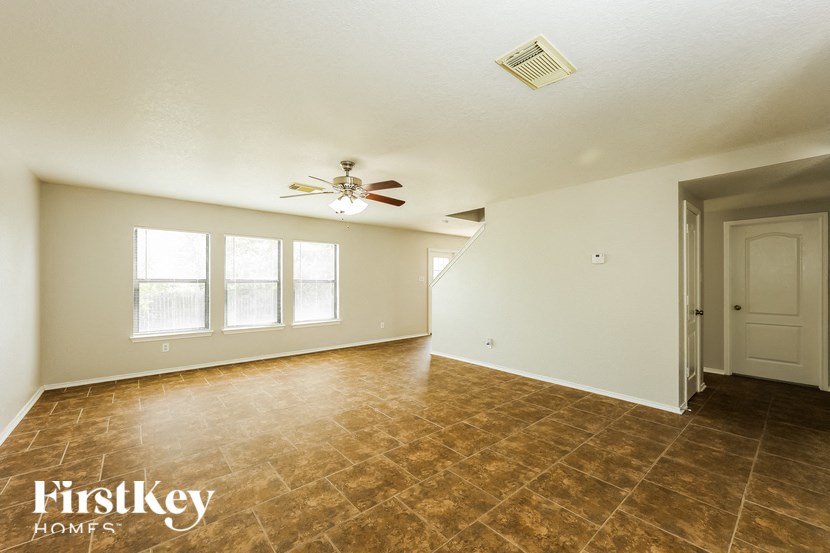 an empty living room with a ceiling fan and a window
