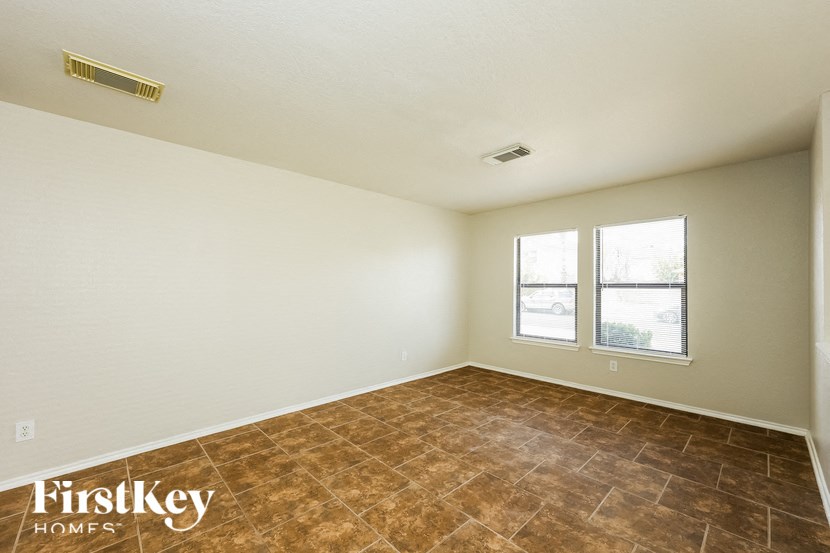 the living room of a white house with brown tile and a window