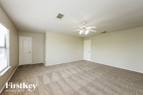a spacious living room with carpet and a ceiling fan
