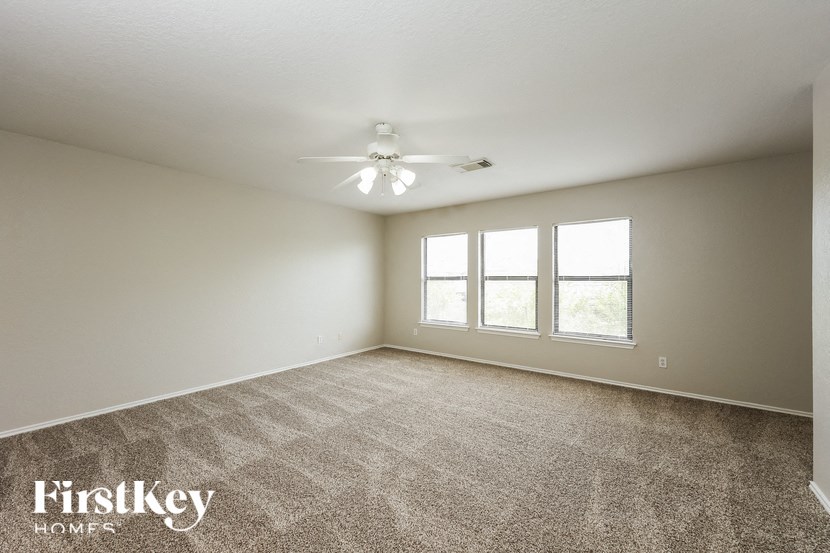 a spacious living room with carpet and a ceiling fan
