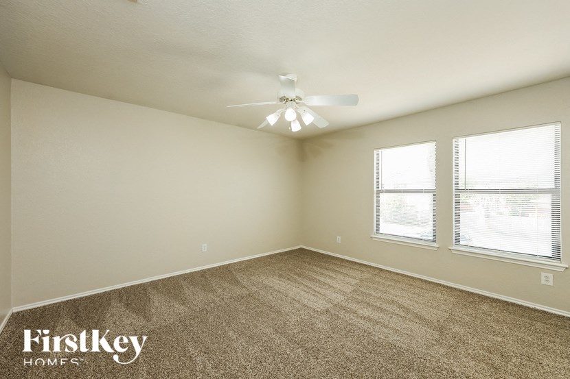 a bedroom with carpet and a ceiling fan and two windows