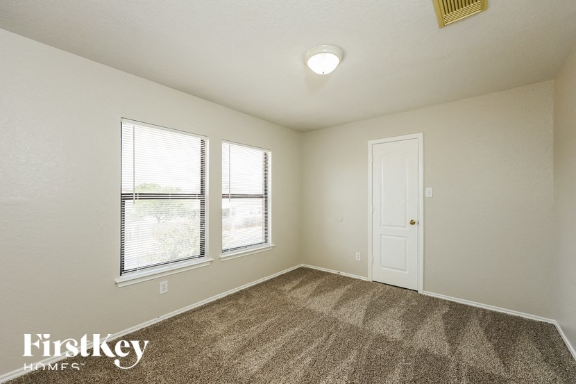 a bedroom with carpet and two windows and a door